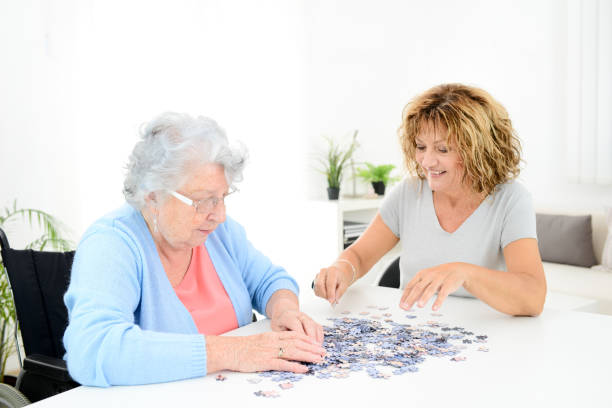 femme mature joyeuse faire puzzle et passer du temps avec la vieille femme senior à la maison - jeu personne agée photos et images de collection